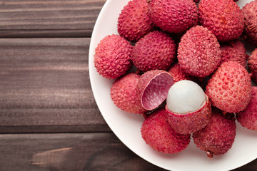 Tasty lychee in plate on wooden table