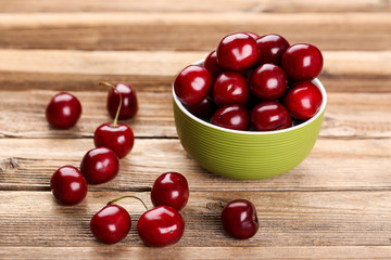 Sweet cherries in bowl on brown wooden table
