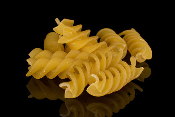 Lot of whole yellow pasta fusilli heap isolated on black glass