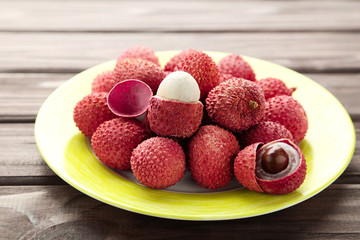 Tasty lychee in plate on wooden table