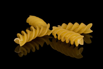 Naklejka premium Group of four whole small yellow pasta fusilli isolated on black glass
