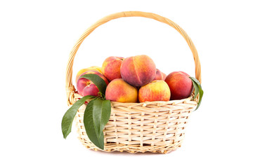 Fresh peaches with green leafs in basket isolated on white background