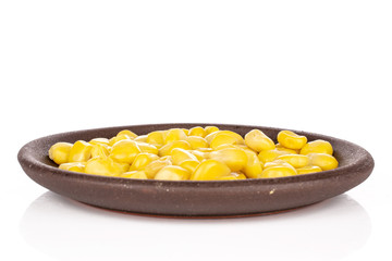 Lot of pieces of canned yellow corn with brown ceramic coaster isolated on white background