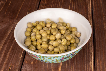 Lot of whole canned pea with blue chinese ceramic bowl on brown wood