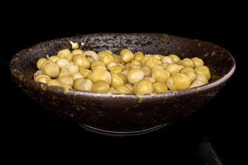 Lot of whole canned pea in glazed bowl isolated on black glass
