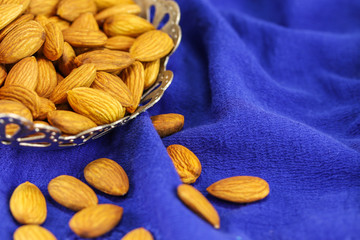 Almonds in a metal vase on a blue background