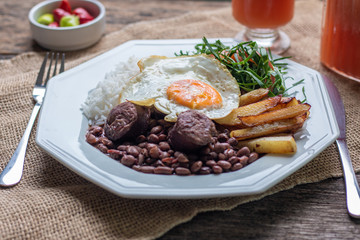 Brazilian food dish. Beans, rice, egg, salad and potatoes. Rustic wood background