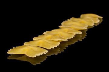 Naklejka premium Lot of whole raw yellow pasta farfalle isolated on black glass
