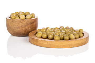 Lot of whole canned pea in bamboo bowl on round bamboo coaster isolated on white background