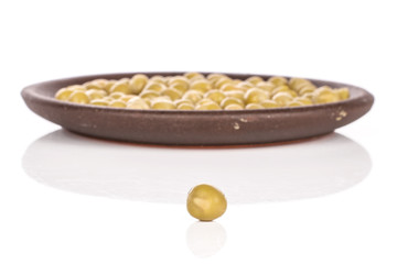 Lot of whole sweet canned pea with brown ceramic coaster isolated on white background