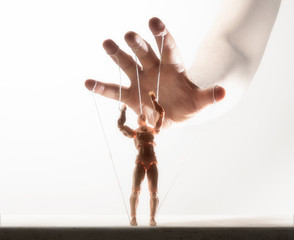 Concept of control. Marionette in human hand. Image on white.