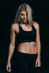 Fototapeta na wymiar Strong blonde sportswoman looking down and posing with black background.
