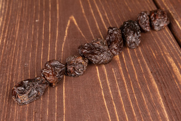Lot of whole dried dark raisin diagonal on brown wood