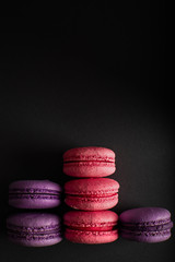 Pink and purple macaroons on a dark background. International Women's Day. French national cuisine. Food shot. closeup