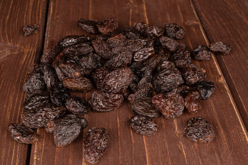 Lot of whole dried dark raisin on brown wood