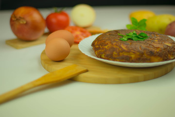 Spanish tortilla with onion on the white plate on a wooden board