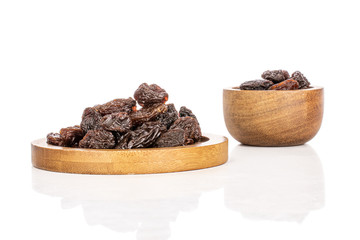 Lot of whole dried dark raisin on round bamboo coaster in bamboo bowl isolated on white background
