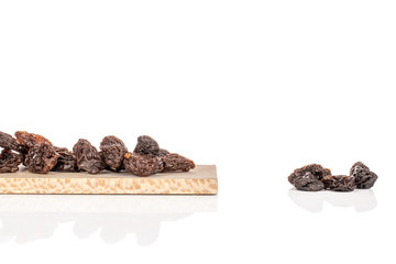 Lot of whole dried dark raisin on wooden cutting board isolated on white background