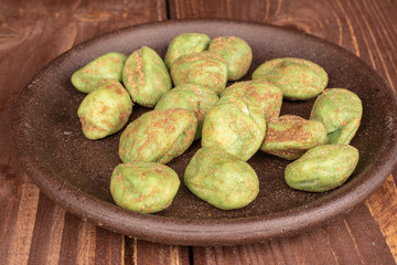 Lot of whole wasabi green peanut with brown ceramic coaster on brown wood