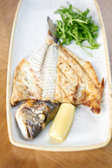 Plate Dorado with arugula and lemon. BBQ seafood. Restaurant menu