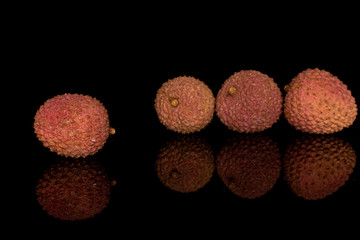 Group of four whole fresh lychee isolated on black glass