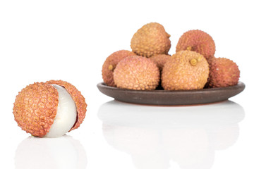 Group of eight whole fresh lychee with brown ceramic coaster isolated on white background