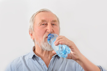 Senior man is drink water from bottle. Pensioner with gray hair and beard.