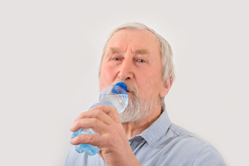 Senior man is drink water from bottle. Pensioner with gray hair and beard.