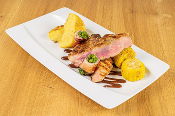 Beautiful pork neck with potato and green beans on white rectangular ceramic plate on lacquered wood
