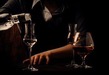 The bartender pours the vodka or tequila in small shot glass on the old bar counter. Vintage wooden...