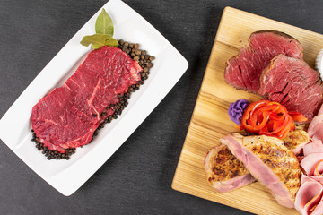 Beautiful meat board and raw beef sirloin with spices on white rectangular ceramic plate flatlay on grey stone