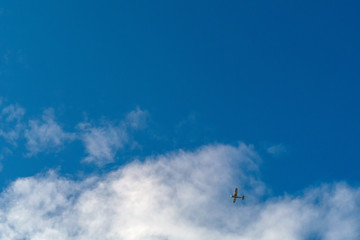 Small commercial airplane flying high in a cloudy sky.