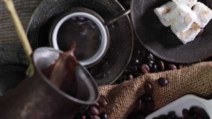 top view of Pouring hot Turkish coffee in a traditional cup on a wooden table with turkish delight