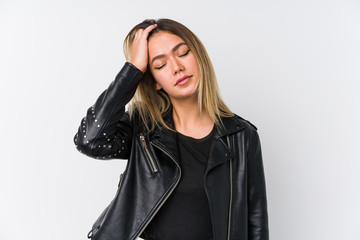 Young caucasian woman wearing a black leather jacket tired and very sleepy keeping hand on head.