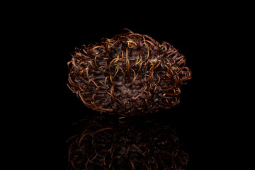 One whole old brown rambutan isolated on black glass