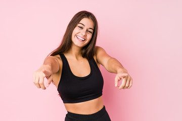 Young caucasian fitness woman doing sport isolated cheerful smiles pointing to front.