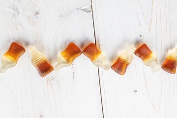 Group of seven whole sweet jelly cola flatlay on white wood