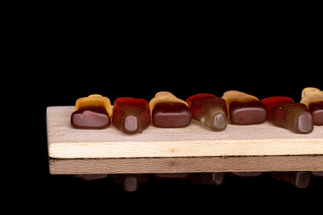 Group of seven whole sweet jelly cola on wooden cutting board isolated on black glass