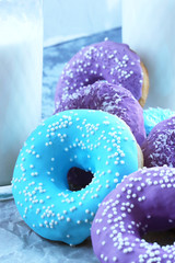 pink and blue doughnuts next to a glass of milk