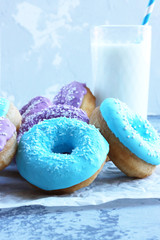 pink and blue doughnuts next to a glass of milk