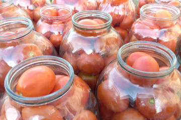 Tomatoes in open jars a lot close up blurred background