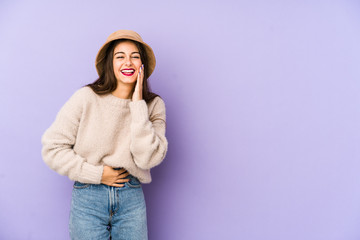 Young caucasian woman isolated on purple background laughs happily and has fun keeping hands on stomach.