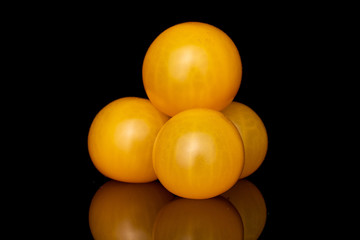Group of four whole fresh yellow tomato stack isolated on black glass