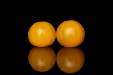 Group of two whole fresh yellow tomato isolated on black glass