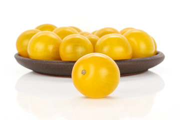 Lot of whole fresh yellow tomato with brown ceramic coaster isolated on white background