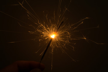 I hold a sparkler in my hand, which sparkles beautifully in different directions.