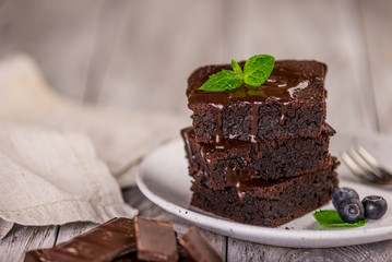 A stack of chocolate brownies on wooden background with mint leaf on top, homemade bakery and dessert