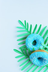 green palm leaves with blue donut on white background, exotic background
