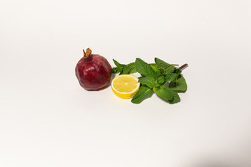 Natural colors of fresh ripe garnet, lemon, mint on white background