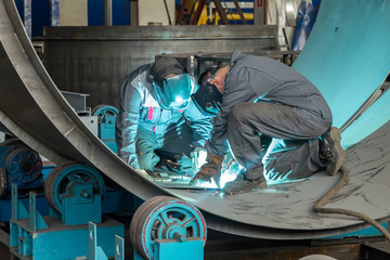 Two workers while doing a welding with arc welder - 326775387